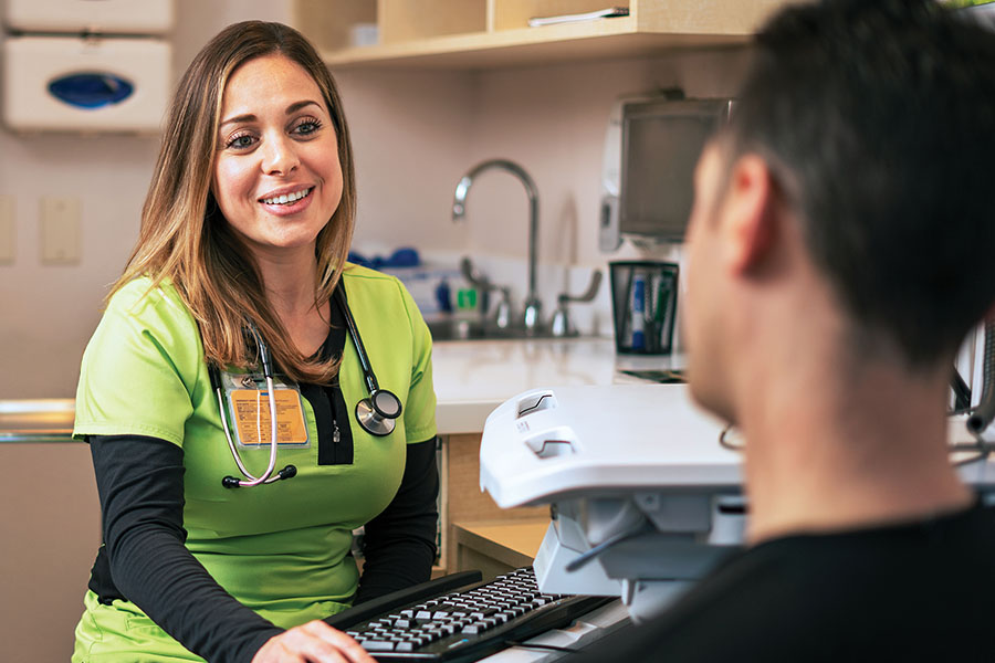 Health care provider at a computer speaking with someone