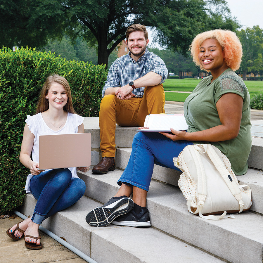 Three university students meet around a laptop computer. 